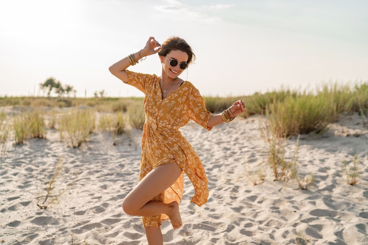 Frau im gelben Kleid tanzt am Strand